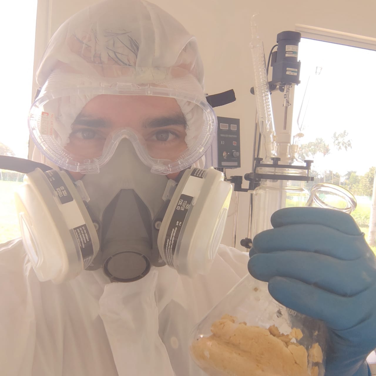 Pharmaceutical powder in a beaker, handled with a respirator.