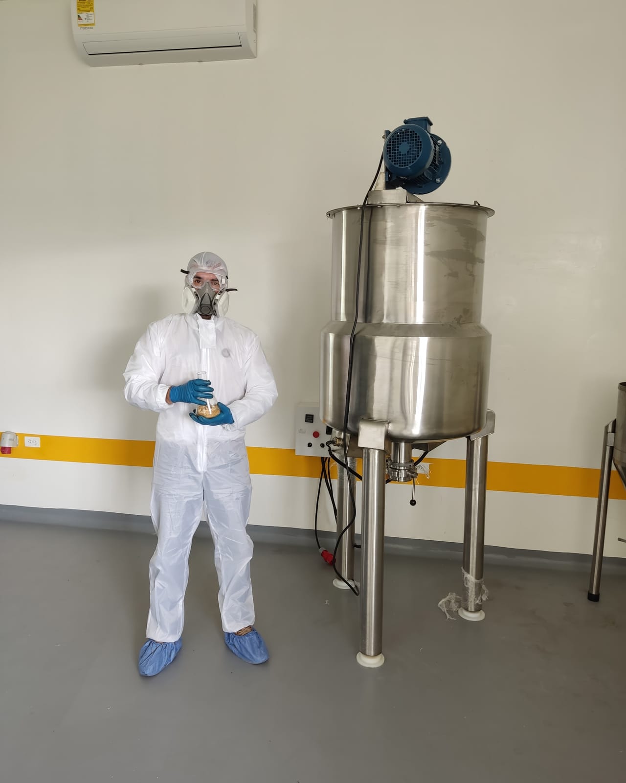 Julian Contreras in full protective gear beside a stainless process reactor.